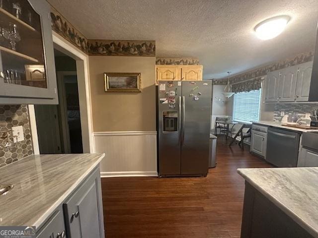 kitchen featuring appliances with stainless steel finishes, a wainscoted wall, dark wood-type flooring, a textured ceiling, and light countertops