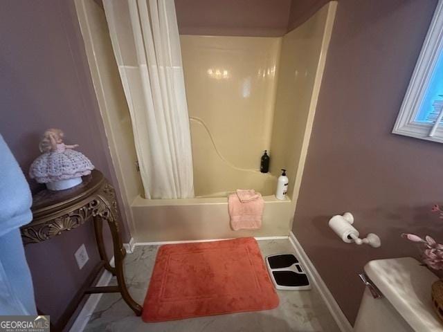 bathroom featuring baseboards, shower / bath combo, and toilet