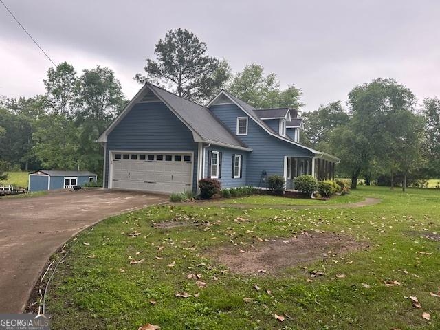 new england style home with driveway, an attached garage, and a front yard