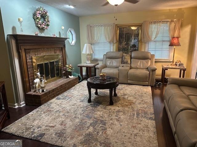 living room featuring wood finished floors, ceiling fan, and a fireplace