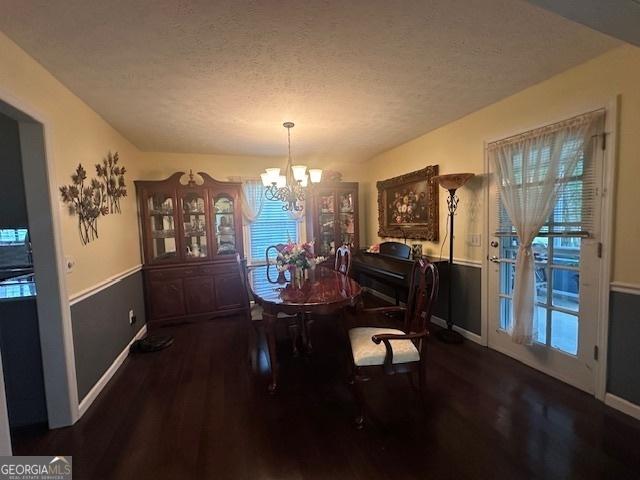 dining area featuring a chandelier, wood finished floors, plenty of natural light, a textured ceiling, and baseboards