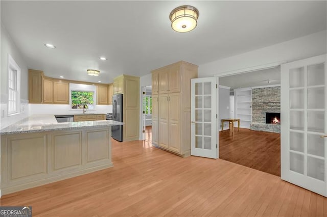 kitchen featuring appliances with stainless steel finishes, light wood-style flooring, light brown cabinets, a peninsula, and french doors