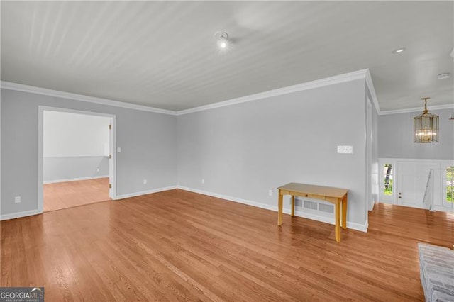 unfurnished living room featuring a chandelier, wood finished floors, ornamental molding, and baseboards