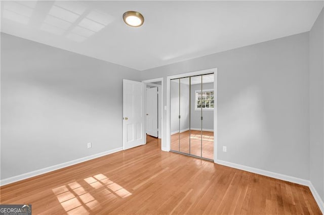 unfurnished bedroom with baseboards, light wood finished floors, and a closet