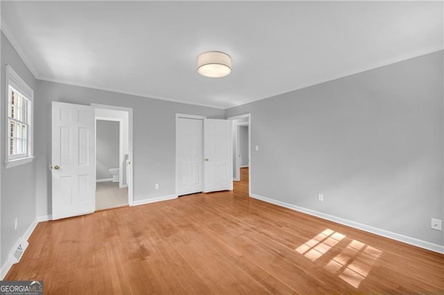 unfurnished bedroom with baseboards, light wood-type flooring, and ornamental molding