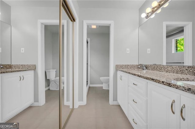 full bathroom with toilet, double vanity, baseboards, and tile patterned floors