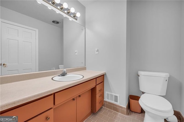 bathroom with toilet, vanity, baseboards, and tile patterned flooring