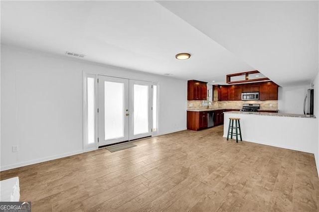 unfurnished living room with light wood finished floors, baseboards, and french doors