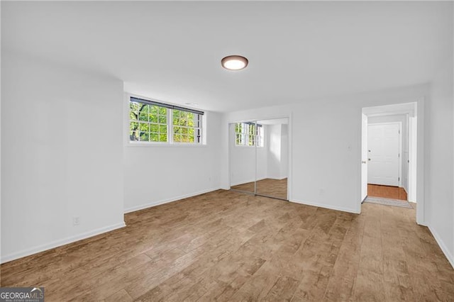 unfurnished bedroom featuring wood finished floors, baseboards, and a closet