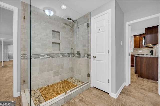 full bathroom featuring a stall shower, recessed lighting, baseboards, backsplash, and wood finished floors