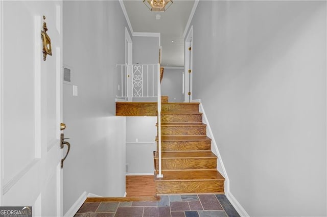 stairway featuring ornamental molding, stone finish floors, and baseboards