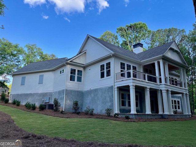 view of side of home with a balcony, a lawn, central air condition unit, a chimney, and roof with shingles