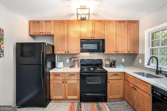 kitchen with black appliances, a sink, tasteful backsplash, and light countertops