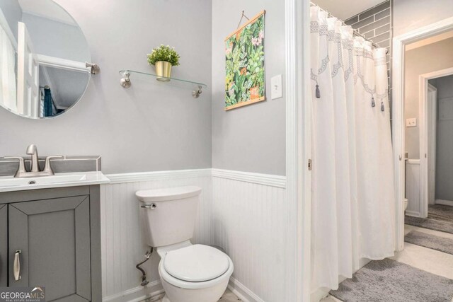 bathroom with toilet, a wainscoted wall, vanity, and a shower with shower curtain