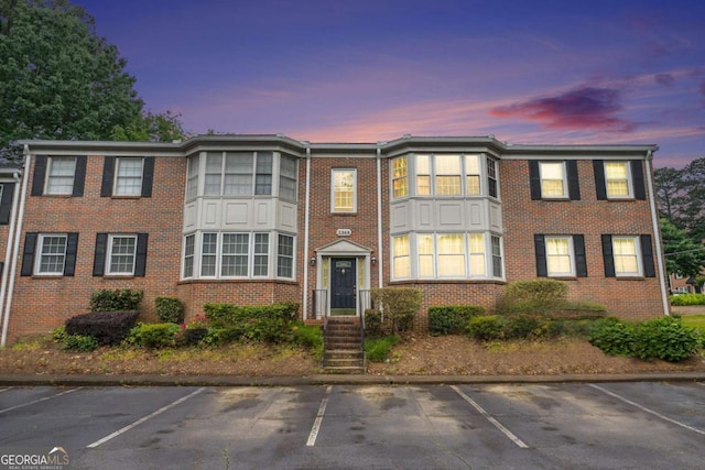 view of property featuring uncovered parking and brick siding