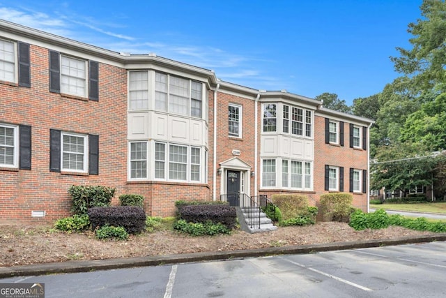 multi unit property featuring brick siding and uncovered parking