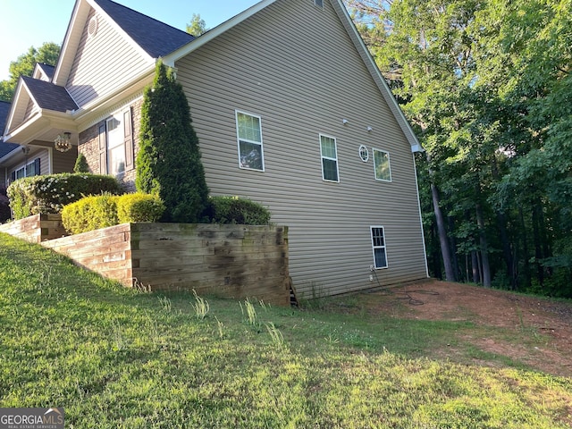view of property exterior featuring a yard and a shingled roof