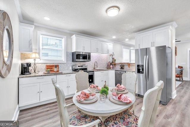 11 Poplar St, Porterdale, GA 30014 - kitchen with stainless steel appliances, a sink, white cabinets, plenty of natural light, and a textured ceiling