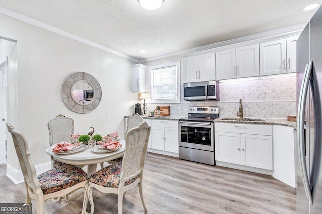 11 Poplar St, Porterdale, GA 30014 - kitchen featuring appliances with stainless steel finishes, a sink, white cabinets, backsplash, and crown molding