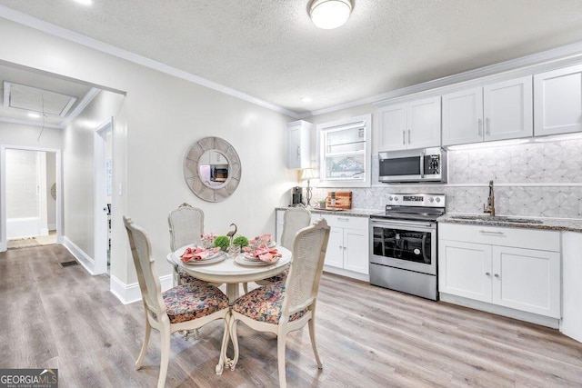 11 Poplar St, Porterdale, GA 30014 - kitchen with stainless steel appliances, a sink, white cabinets, backsplash, and light wood-style flooring