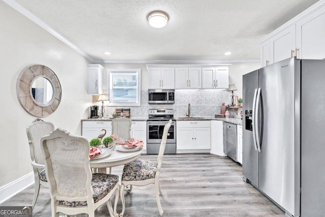 11 Poplar St, Porterdale, GA 30014 - kitchen with appliances with stainless steel finishes, a sink, crown molding, a textured ceiling, and white cabinets