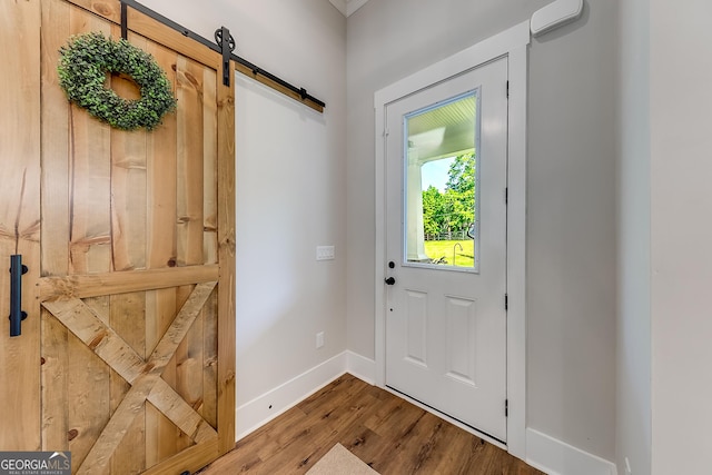 doorway with a barn door, wood finished floors, and baseboards