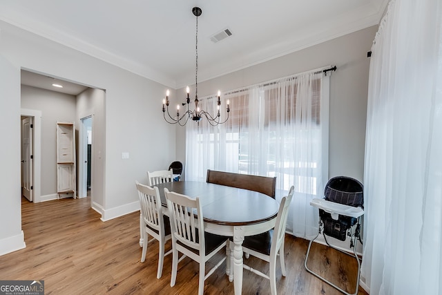 dining space featuring light wood finished floors, ornamental molding, a chandelier, and baseboards