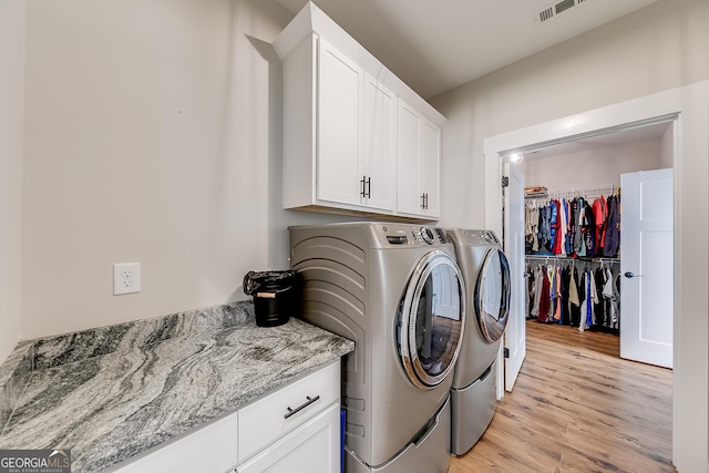 washroom featuring washer and dryer, cabinet space, and light wood finished floors