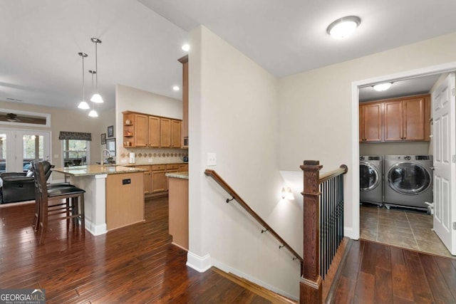 kitchen featuring independent washer and dryer, dark wood-style floors, open shelves, a kitchen breakfast bar, and light stone counters