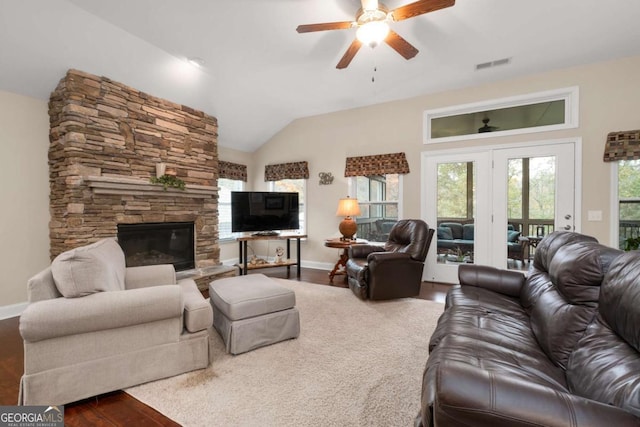 living area with ceiling fan, a fireplace, wood finished floors, baseboards, and vaulted ceiling