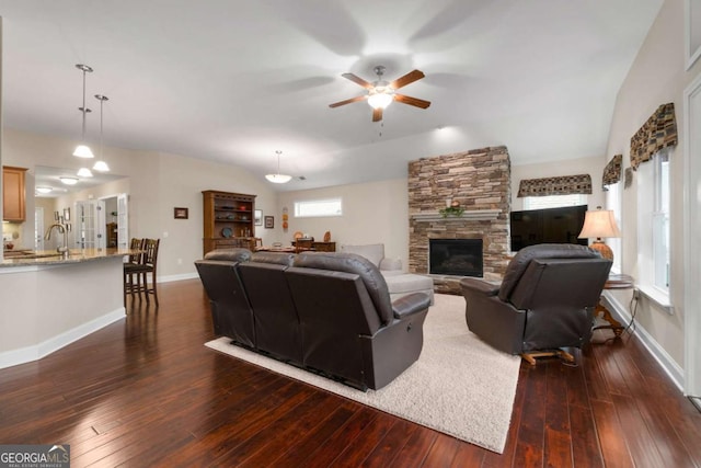 living room featuring a ceiling fan, dark wood-style floors, a fireplace, and baseboards