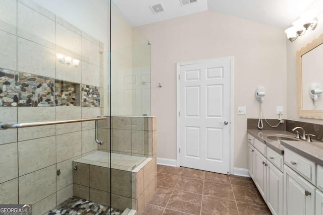 bathroom with a shower stall, lofted ceiling, vanity, tile patterned flooring, and baseboards