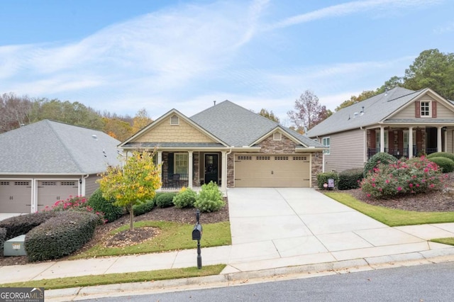 craftsman-style home with covered porch, a garage, stone siding, and driveway