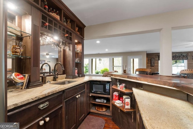 bar area with a sink, black microwave, dark wood-style flooring, and recessed lighting