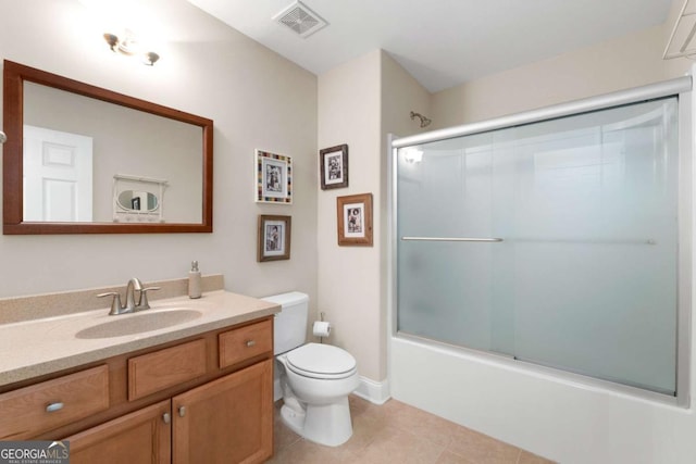 bathroom featuring toilet, tile patterned flooring, vanity, and bath / shower combo with glass door
