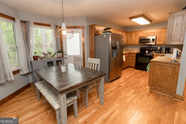 kitchen with stainless steel appliances, a sink, light wood-type flooring, light countertops, and baseboards