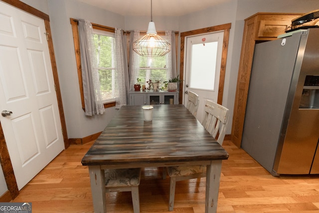 dining space featuring light wood-type flooring and baseboards