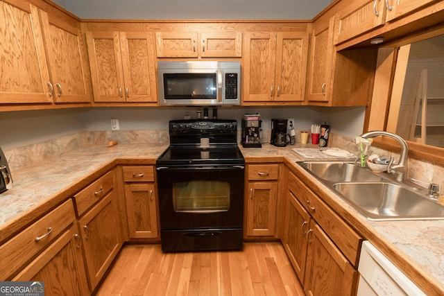 kitchen featuring stainless steel microwave, black range with electric stovetop, a sink, and light countertops