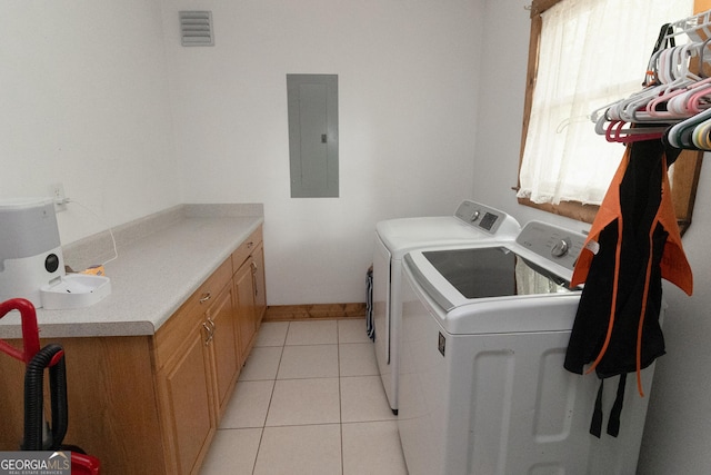 washroom featuring electric panel, separate washer and dryer, light tile patterned floors, and cabinet space