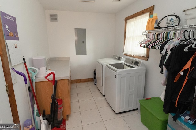 clothes washing area with electric panel, washing machine and dryer, light tile patterned flooring, and baseboards
