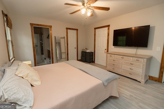 bedroom with light wood-style flooring, ceiling fan, baseboards, and ensuite bathroom