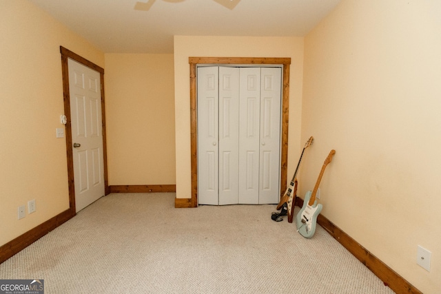 unfurnished bedroom featuring light colored carpet, baseboards, ceiling fan, and a closet