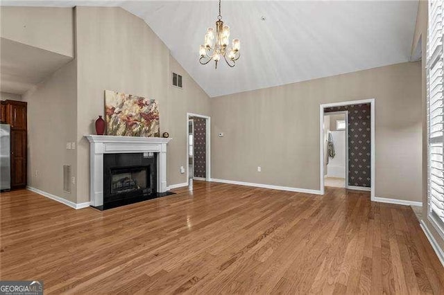 226 Hames Rd Unit 335, Woodstock, GA 30188 - unfurnished living room with a chandelier, light wood finished floors, high vaulted ceiling, a fireplace with flush hearth, and healthy amount of natural light