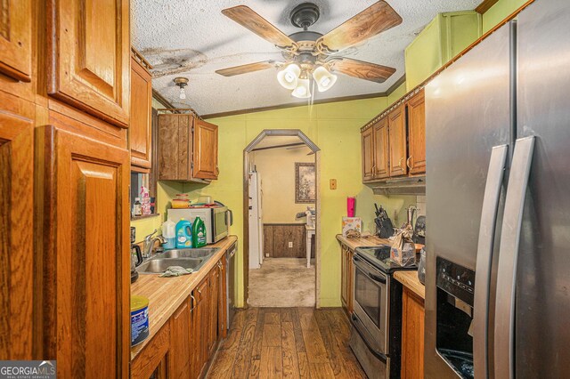 2249 Jackson Lake Rd, Mansfield, GA 30055 - kitchen with stainless steel appliances, a sink, arched walkways, a textured ceiling, and dark wood-style floors