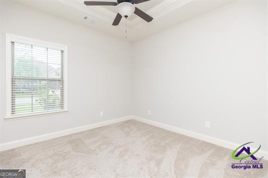 empty room featuring plenty of natural light, carpet floors, ceiling fan, and a raised ceiling