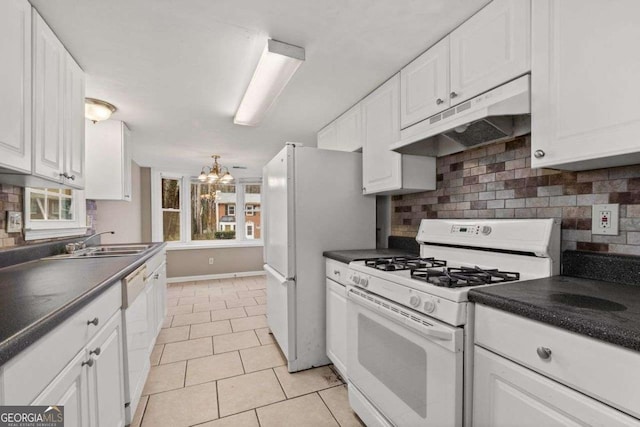 kitchen with white appliances, under cabinet range hood, dark countertops, white cabinetry, and a chandelier