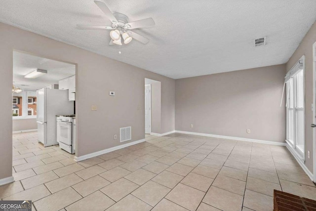 unfurnished room with ceiling fan, a textured ceiling, light tile patterned floors, and baseboards