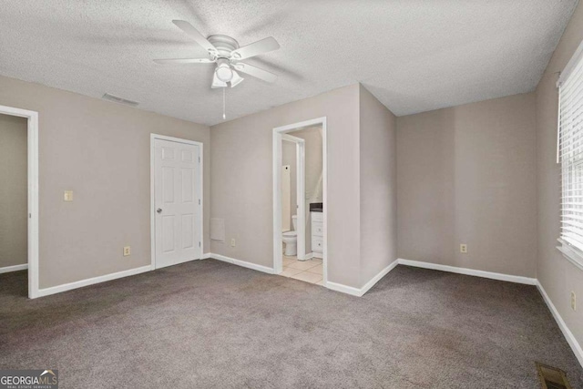 unfurnished bedroom featuring carpet flooring, a textured ceiling, multiple windows, and baseboards