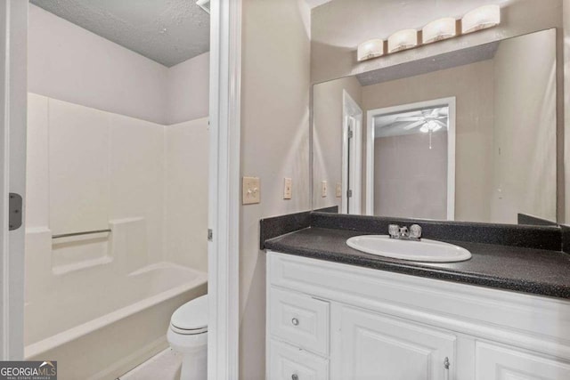 full bathroom featuring ceiling fan, vanity, toilet, shower / washtub combination, and a textured ceiling