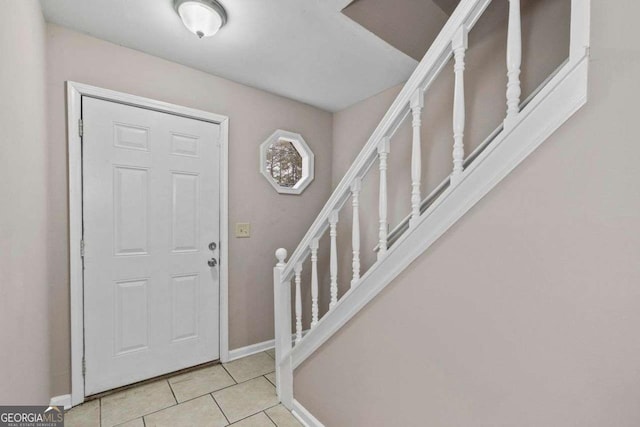 entryway with baseboards, stairs, and light tile patterned floors